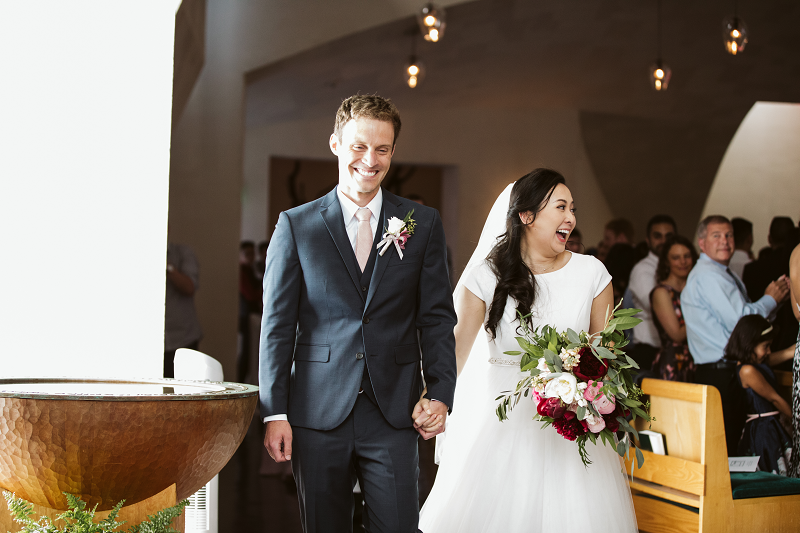 a happy couple processes out of the Chapel after their wedding. 