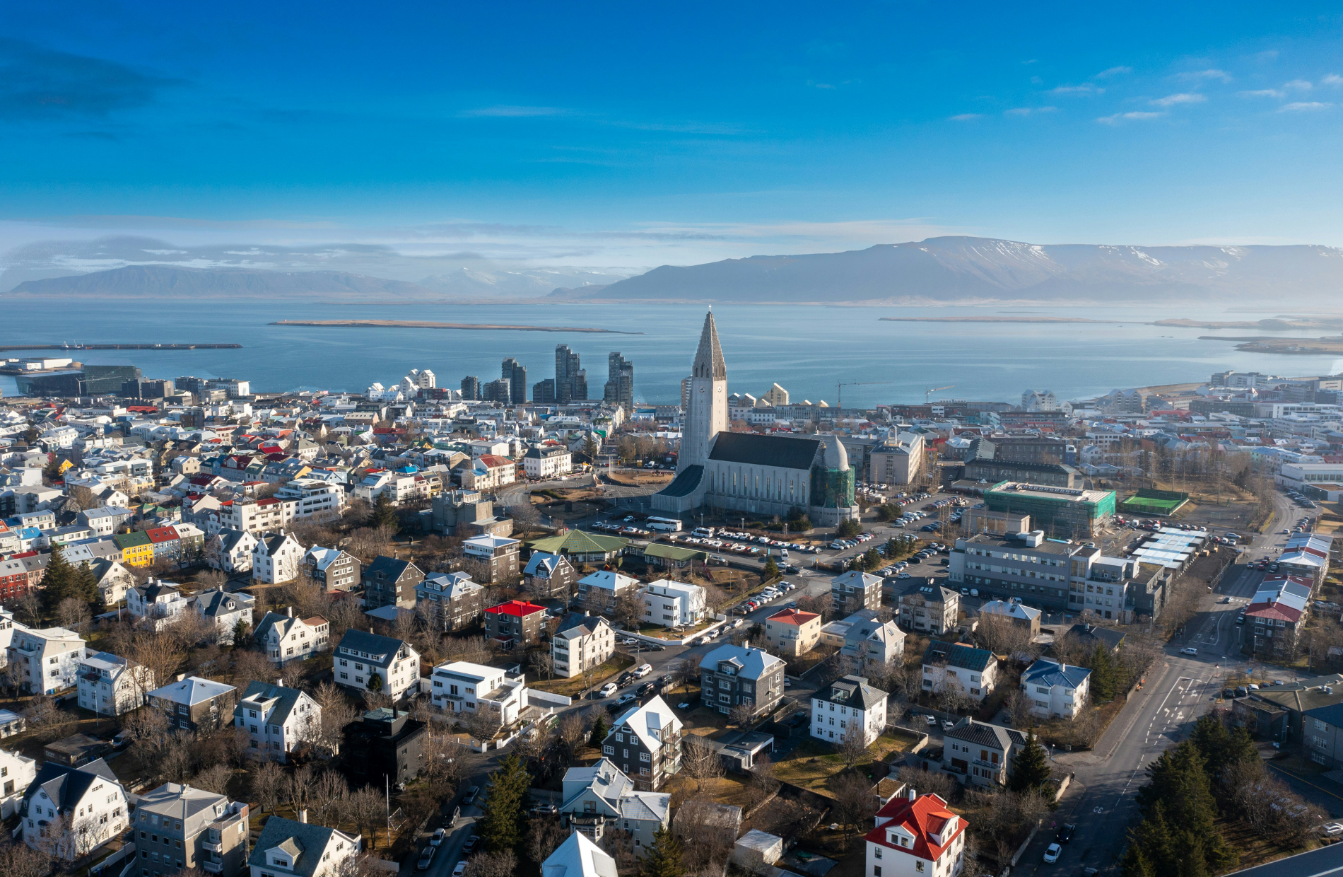 Aerial view of a city with the sea/harbor and mountains in the background