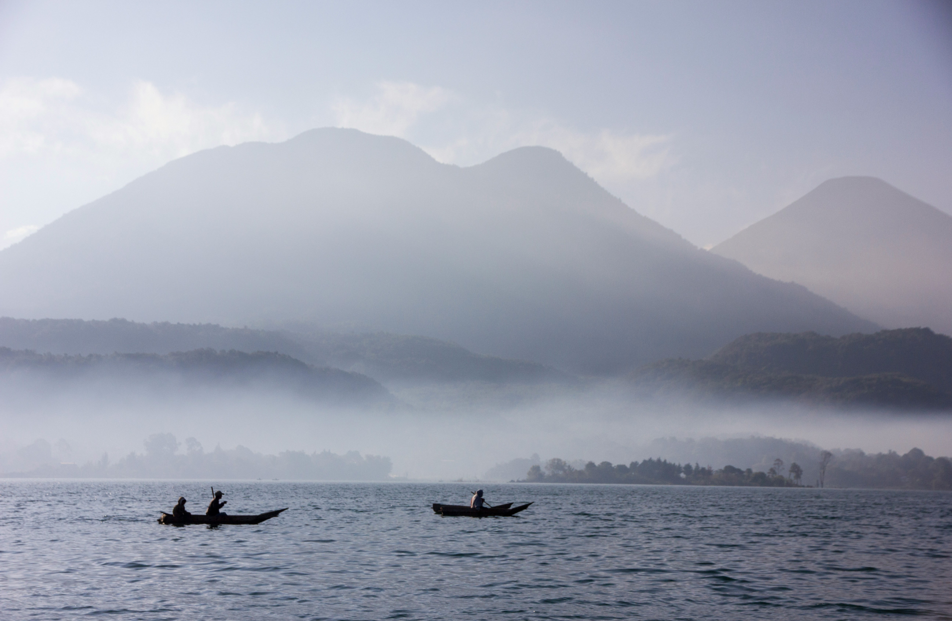two boats with people on a sea with mountains in the background