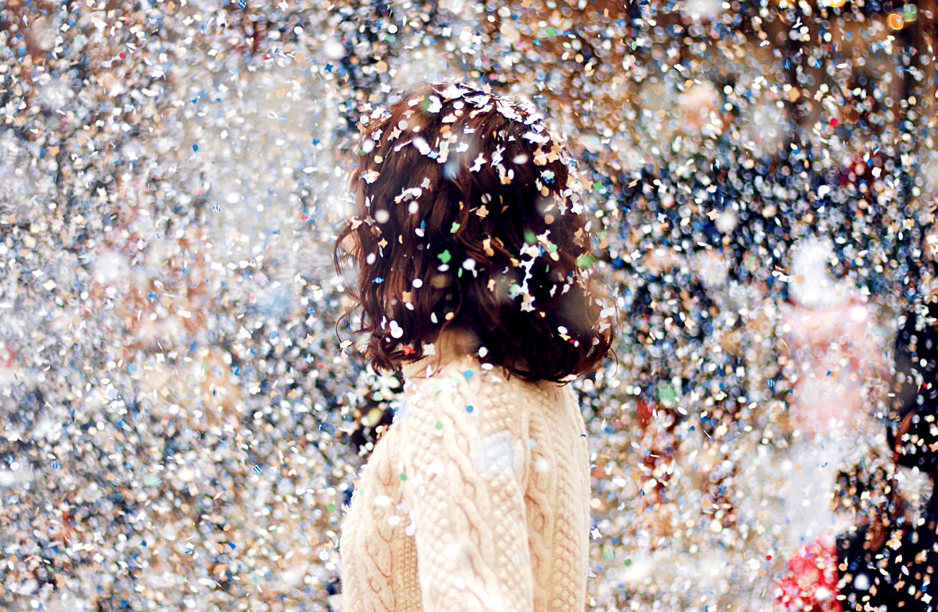 a woman facing away from the camera with confetti all around them