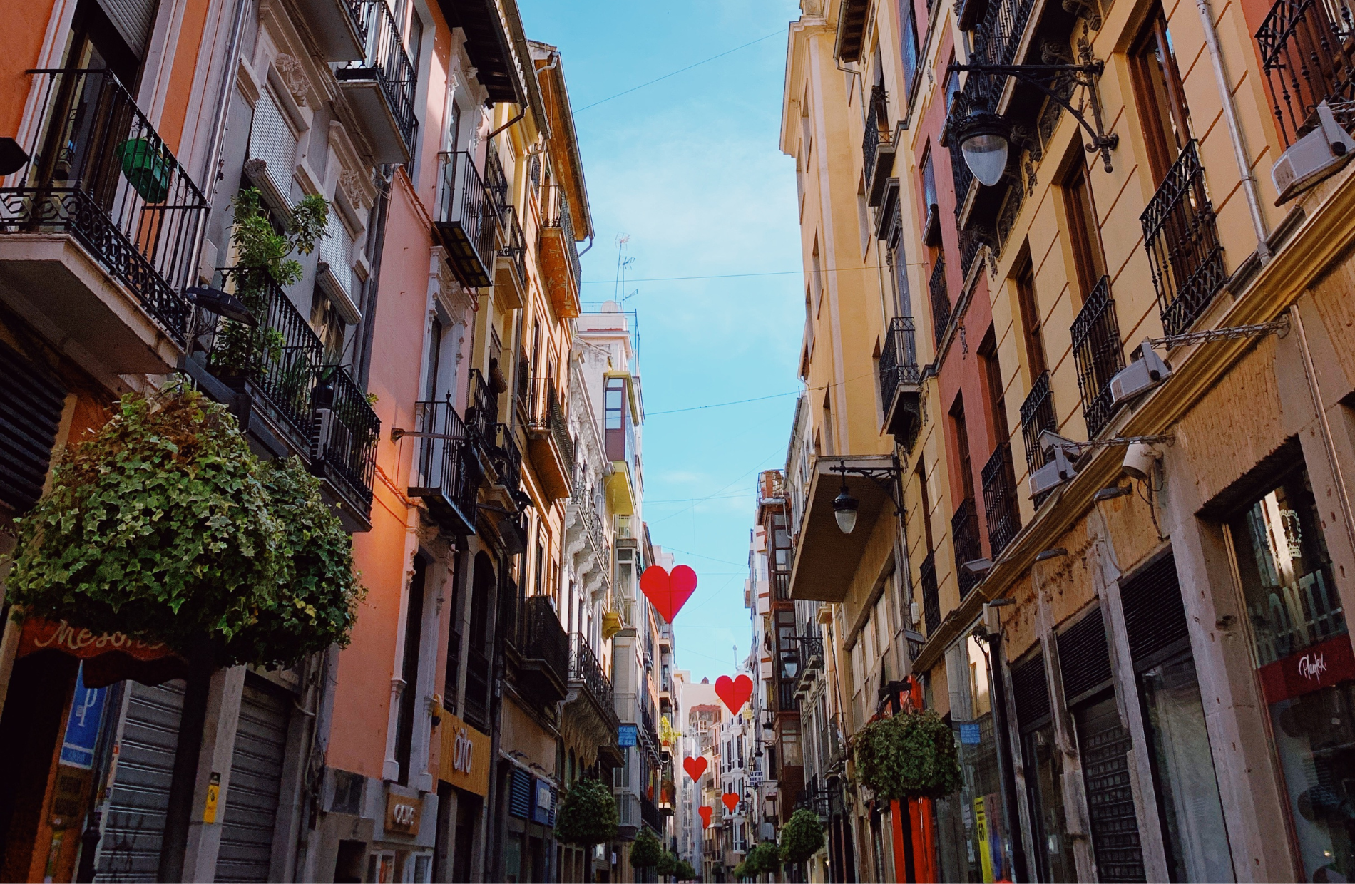 a street lined with gothic style homes with balconies and large heart-shaped decorations above the street