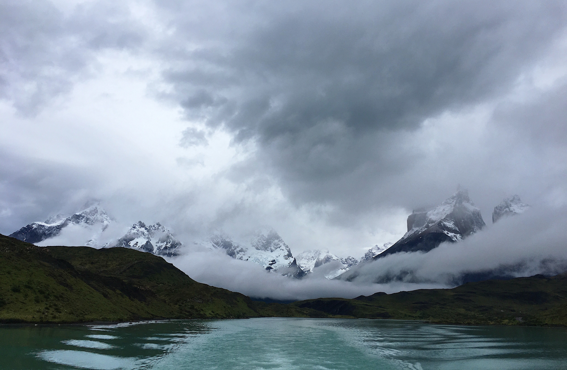 cloudy view of mountain ranges and lake in the foreground