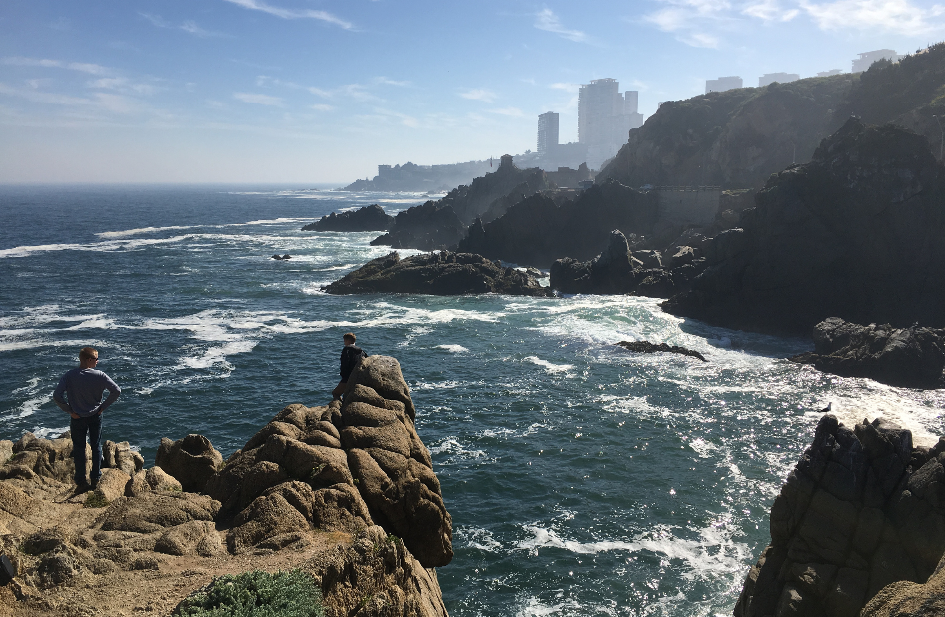 people standing on a cliff side looking at the Chilean coast line