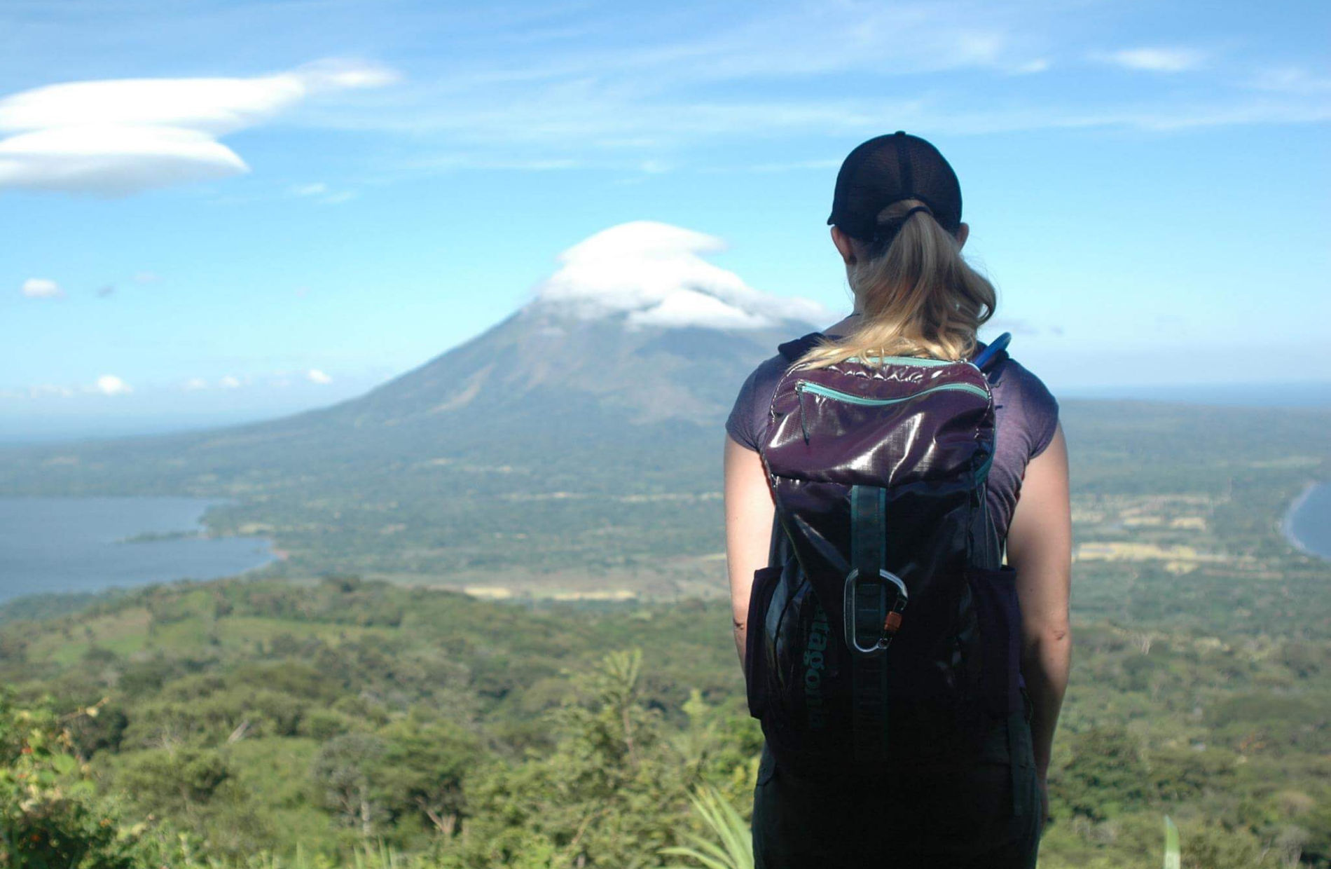 the back of a woman with a backpack viewing the large mountain in the background