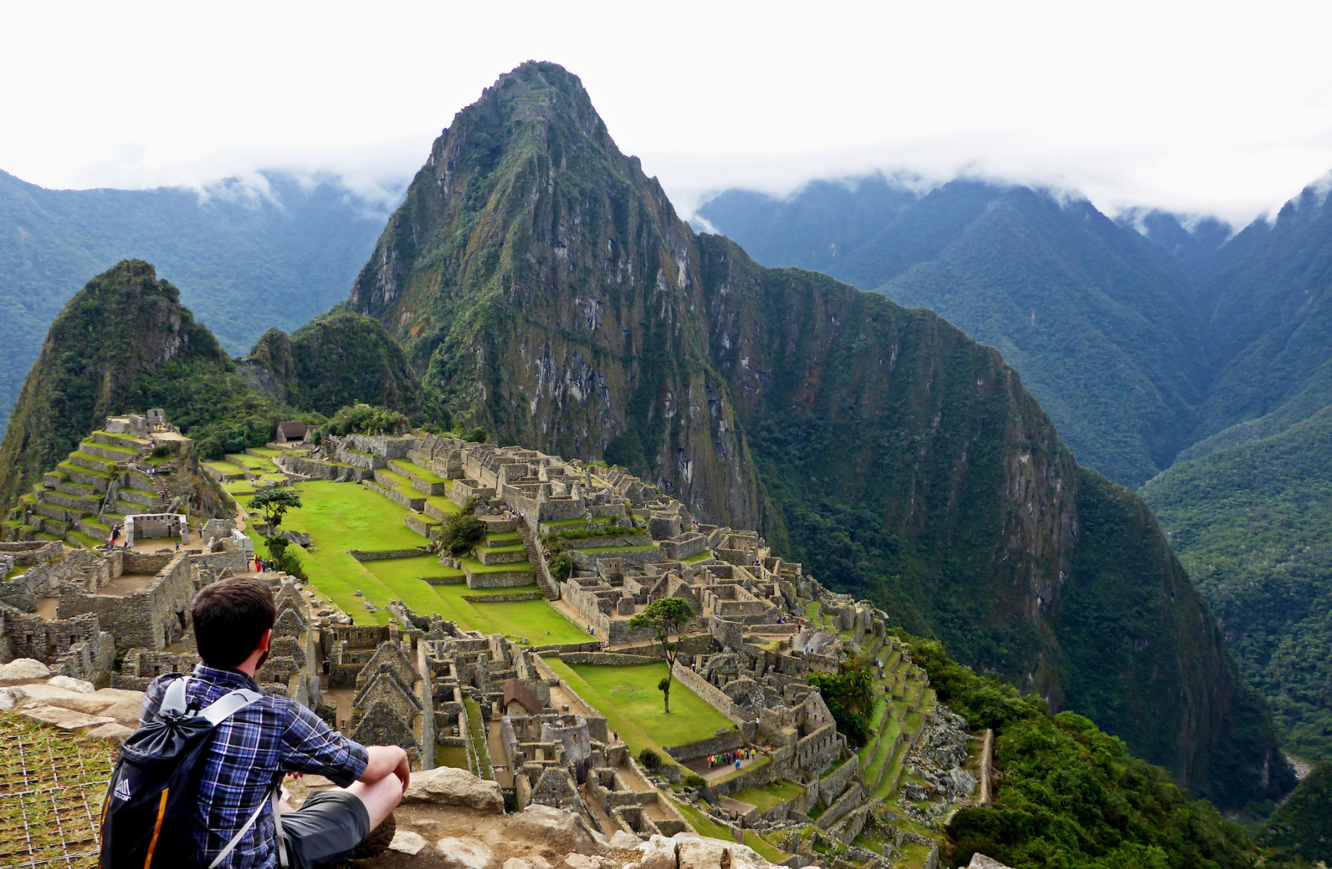 man sitting on an edge overseeing Machu Picchu