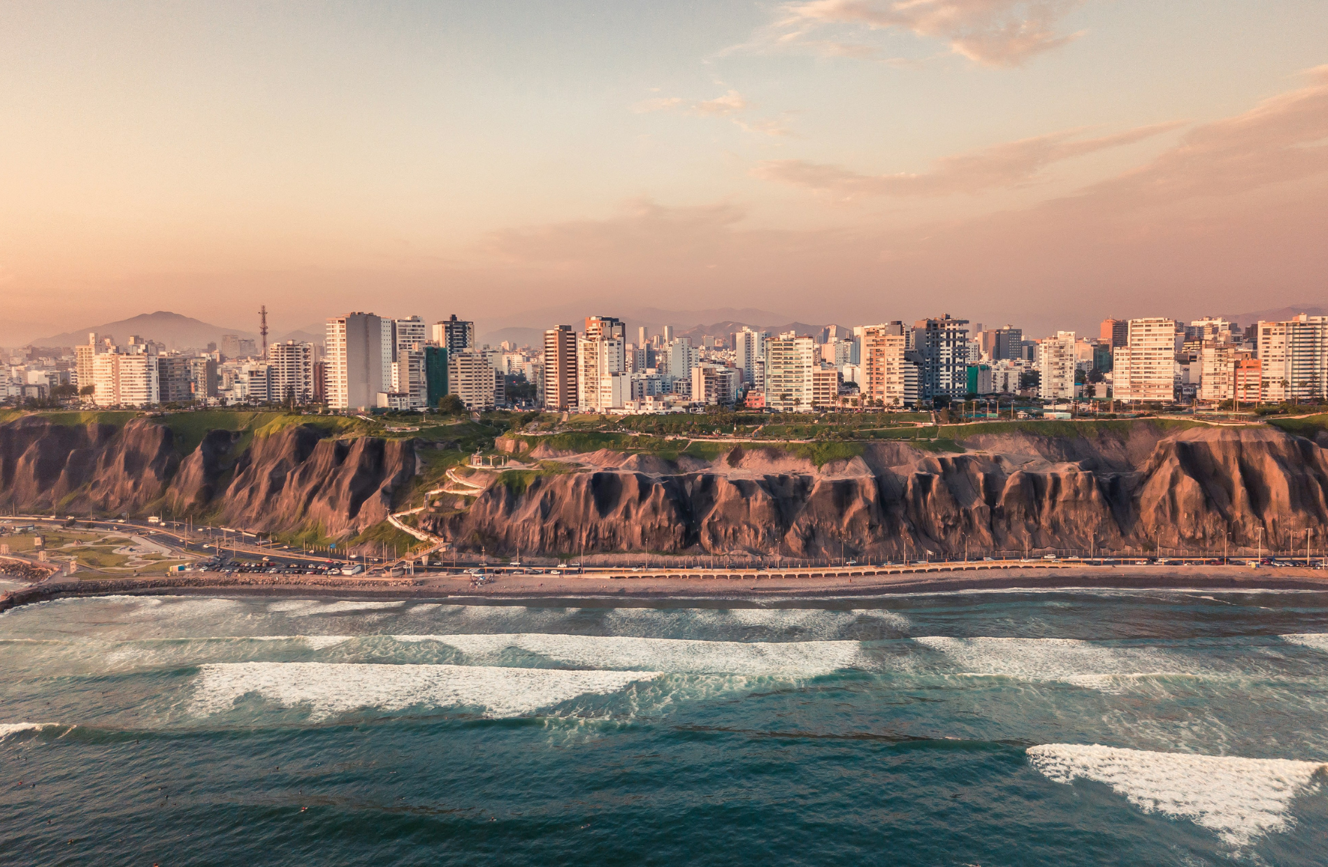 road near beach with buildings on a cliffside