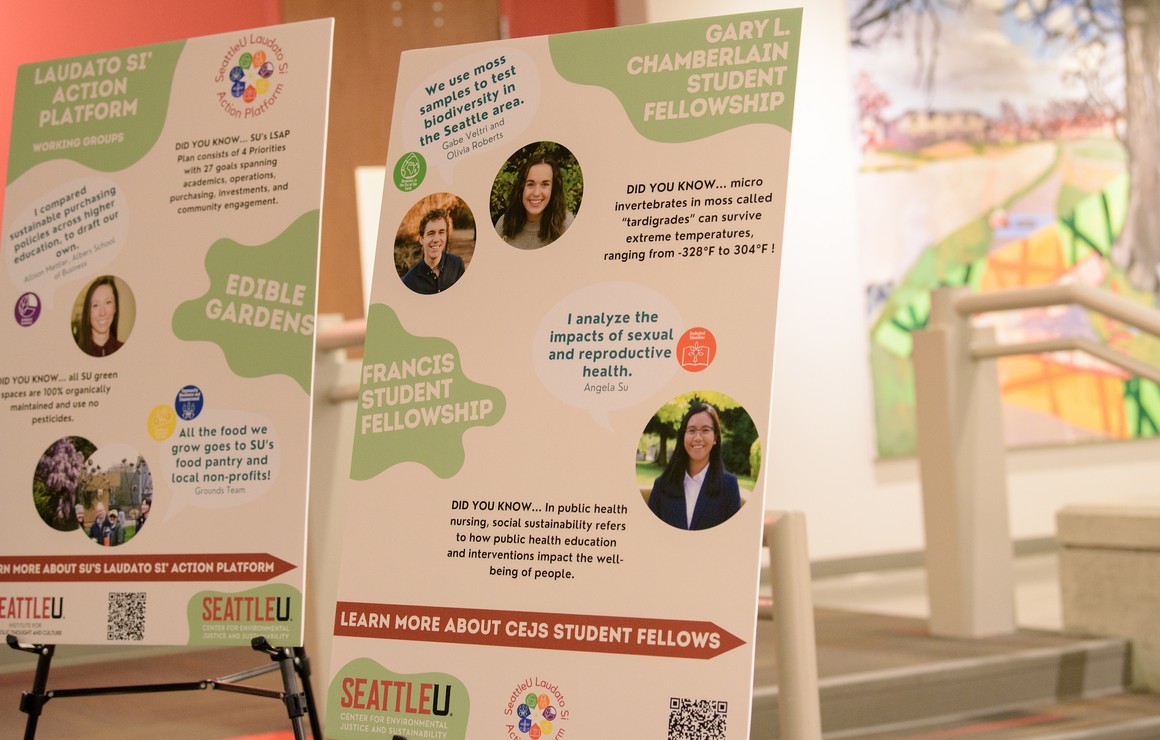 White and green posterboard showing photos of past fellows and topics of research such as reproductive health and biodiversity