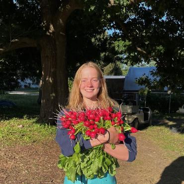 A headshot of Nikki outside while holding a large bouquet of flowers