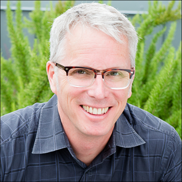 Paul Beaudet in front of green background smiling