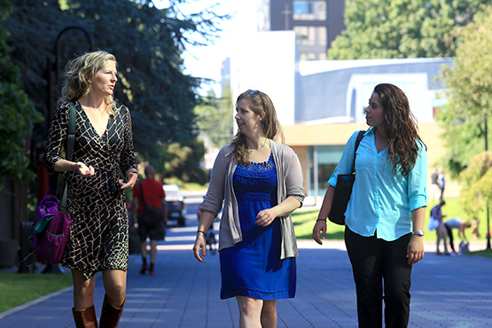 Three graduate students walking along the lower mall on campus