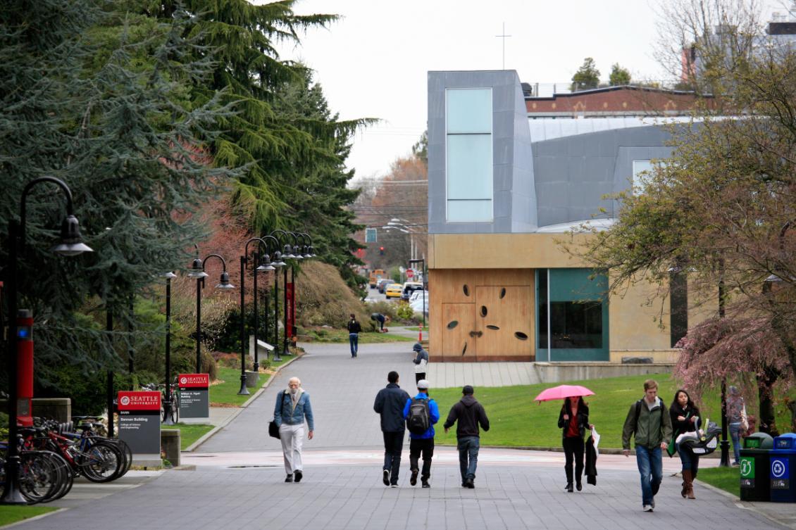 A group of people walking down a sidewalk in front of a building.