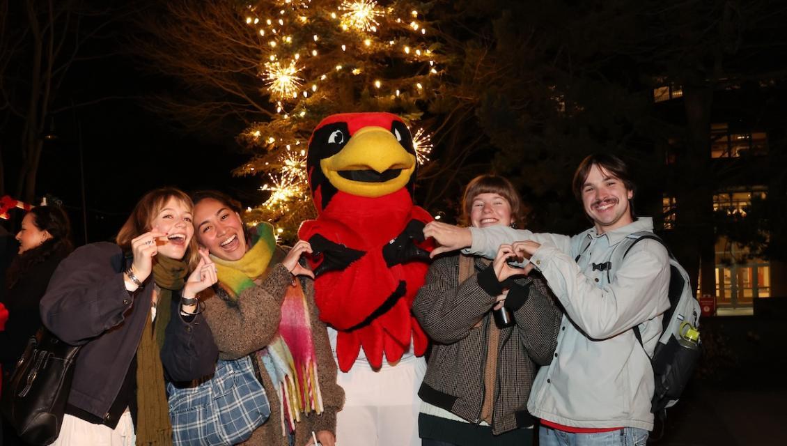 Christmas tree lighting four students around Rudy