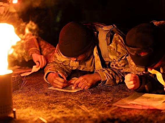 ROTC cadet writing on ground