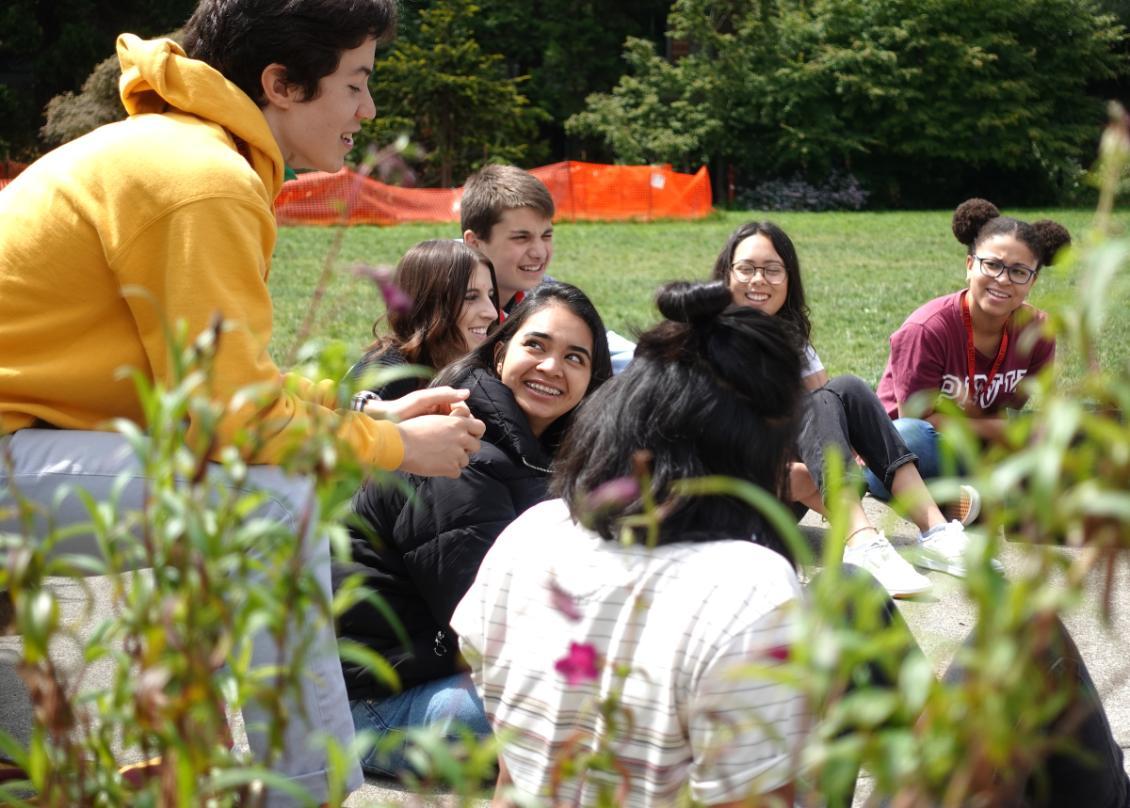 A group of people sitting on the ground in a park.