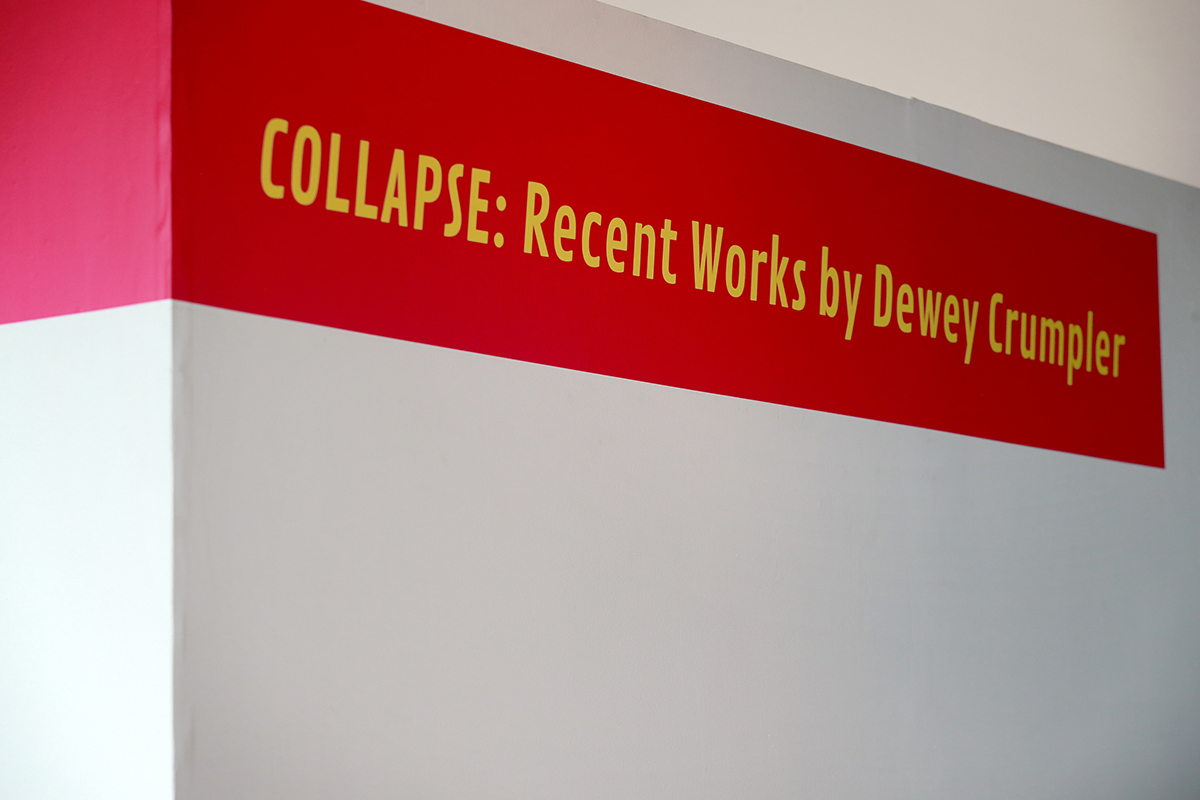 Image of pink banner with yellow letters that say Collapse: Recent Works by Dewey Crumpler