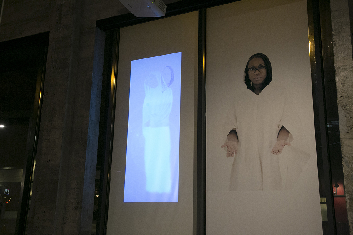 Two images on a window of a person dressed in white with arms outstretched toward the viewer