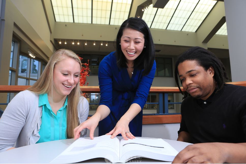 professor and students looking at a book and talking