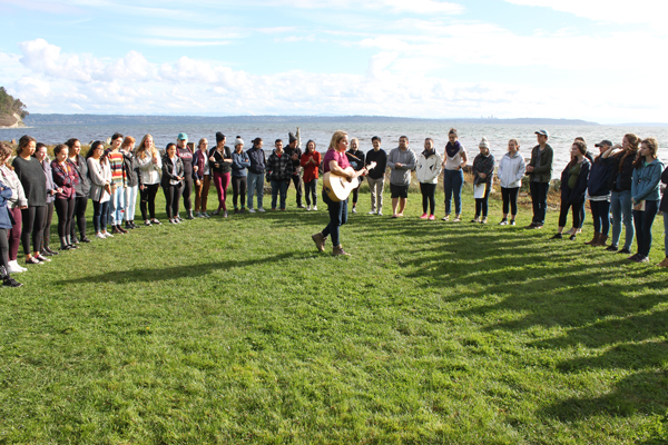 A group of students standing in a circle outdoors at a student retreat