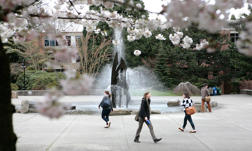 Students walking on campus past the fountain