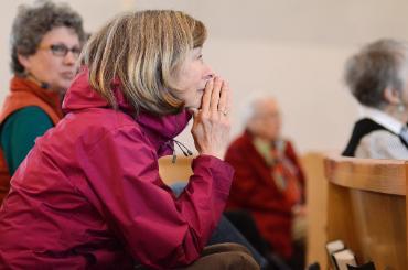 woman alum praying in chapel