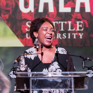 A photo of Essence Russ standing in front of a podium at an SU Gala