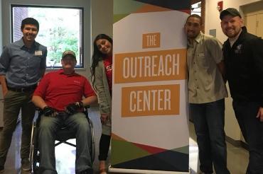 Students standing next to Outreach Center sign