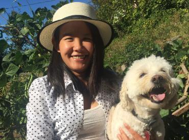 A portrait of Elly Hein Trinh holding a white fluffy dog
