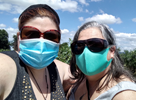 A photo of two women standing in a field with face masks on