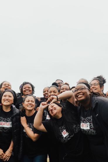 Group of 10 BIPOC individuals wearing black t-shirts standing together and smiling