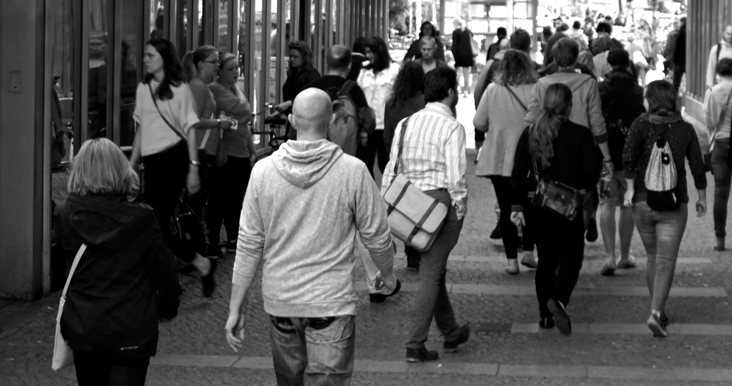 Black and white image of pedestrians walking on a busy street