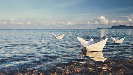 three paper boats on a lake