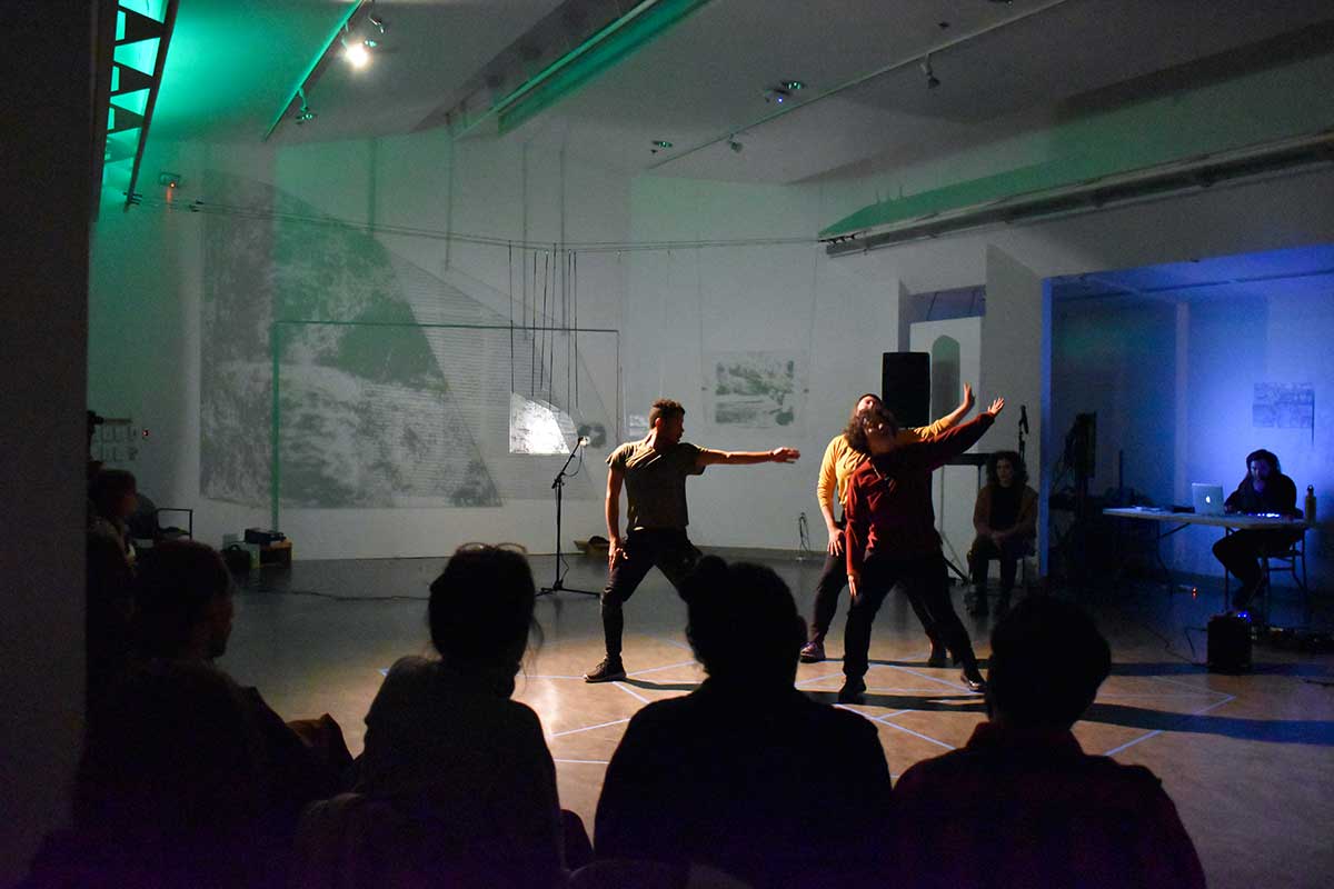 Performers dancing in Vachon Gallery with green and blue lights and video projection