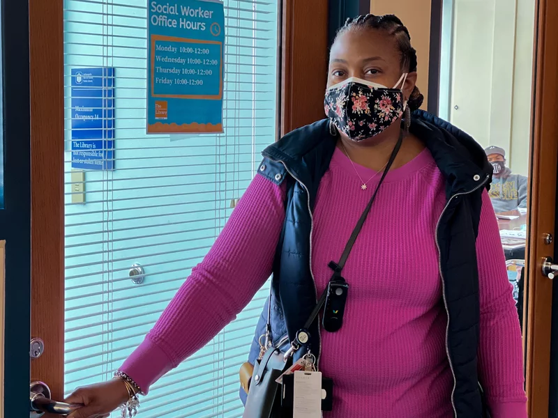 Social worker wearing a mask and standing in front of a library front door