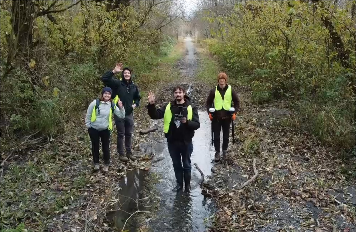 Students standing in a watershed area wearing raingear