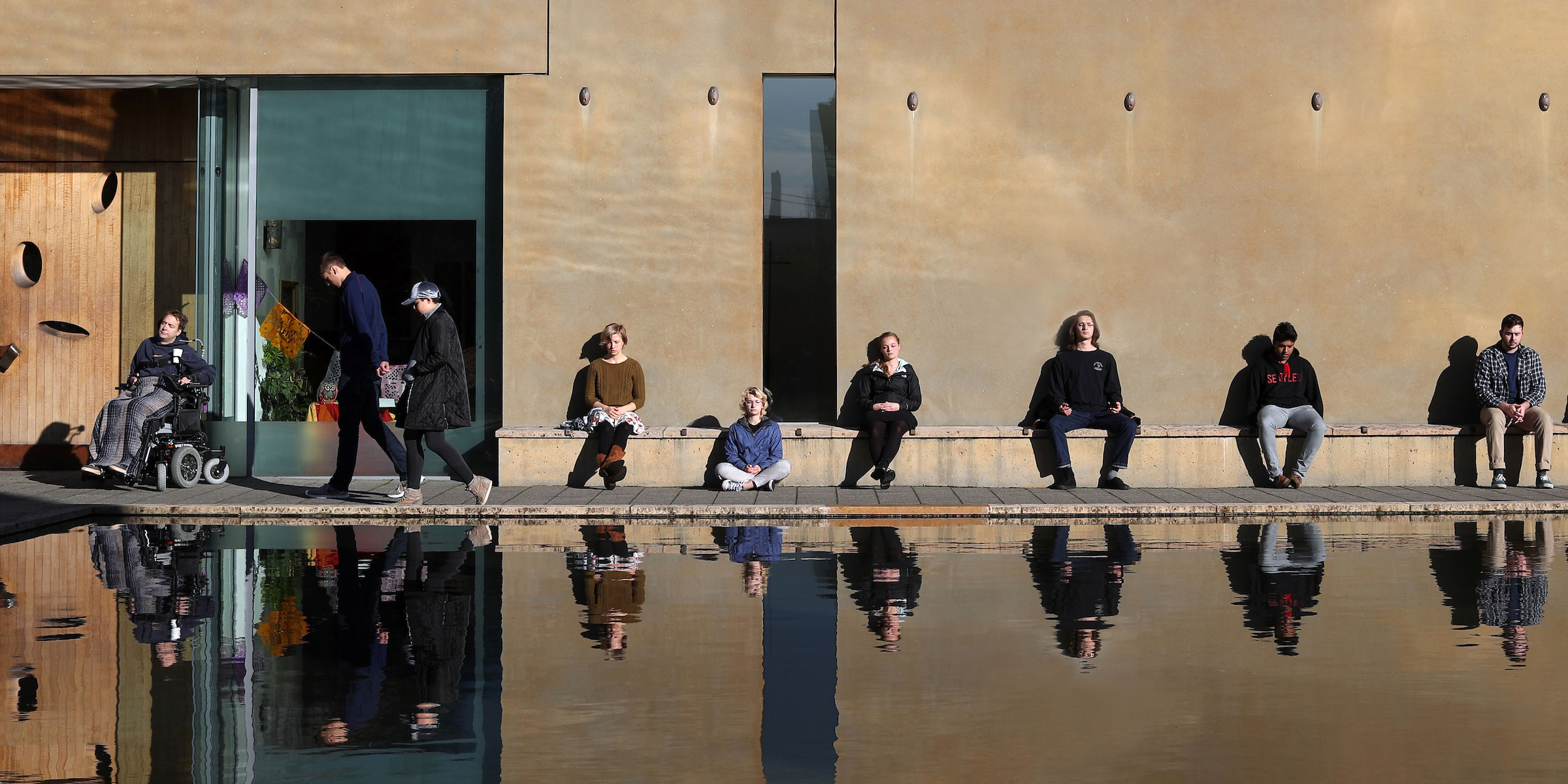 students soak in the sun on the benches of St. Ignatius chapel and the Reflecting Pool