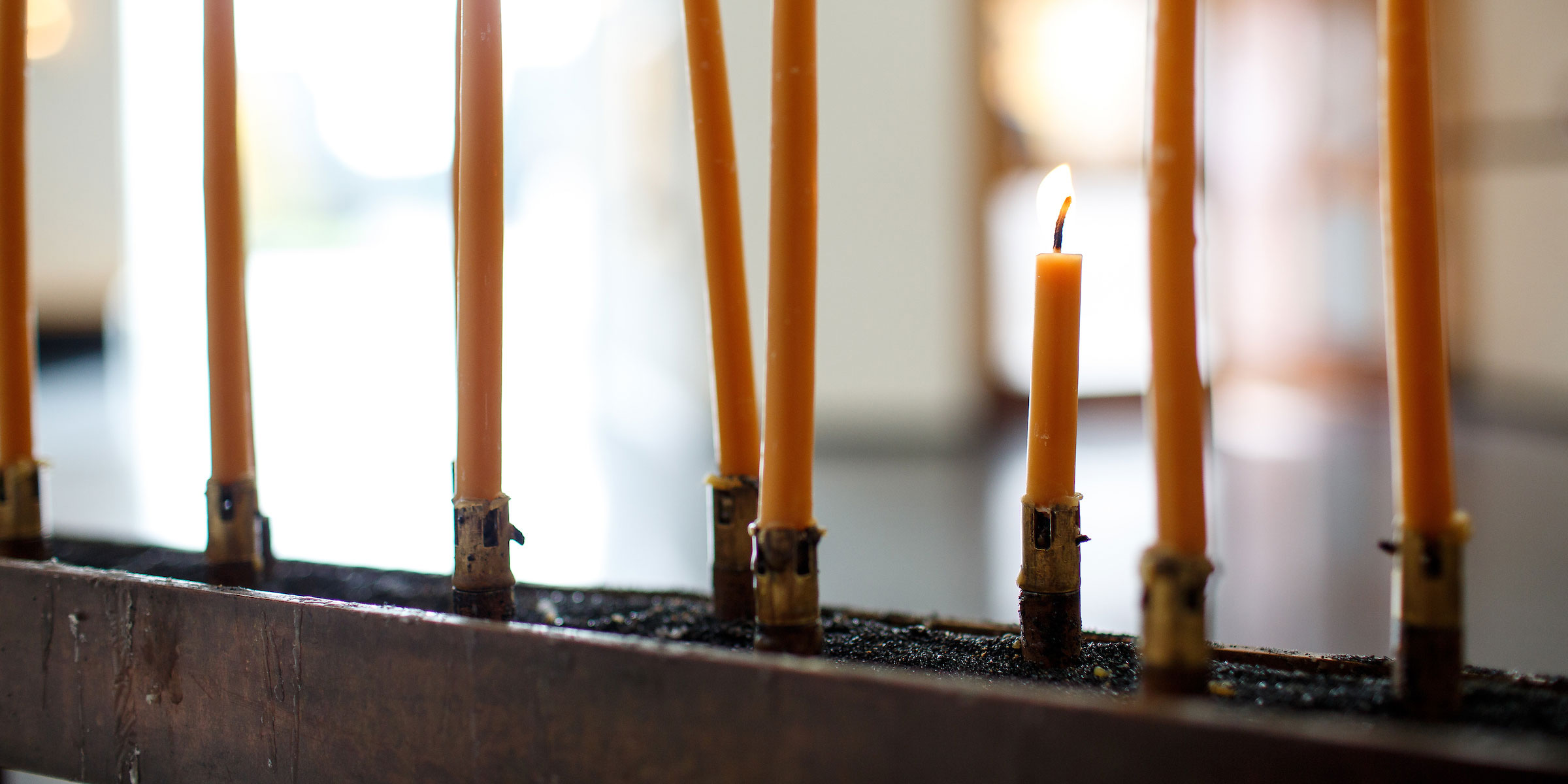 a closeup of thin taper beeswax candles inside the St. Ignatius chapel