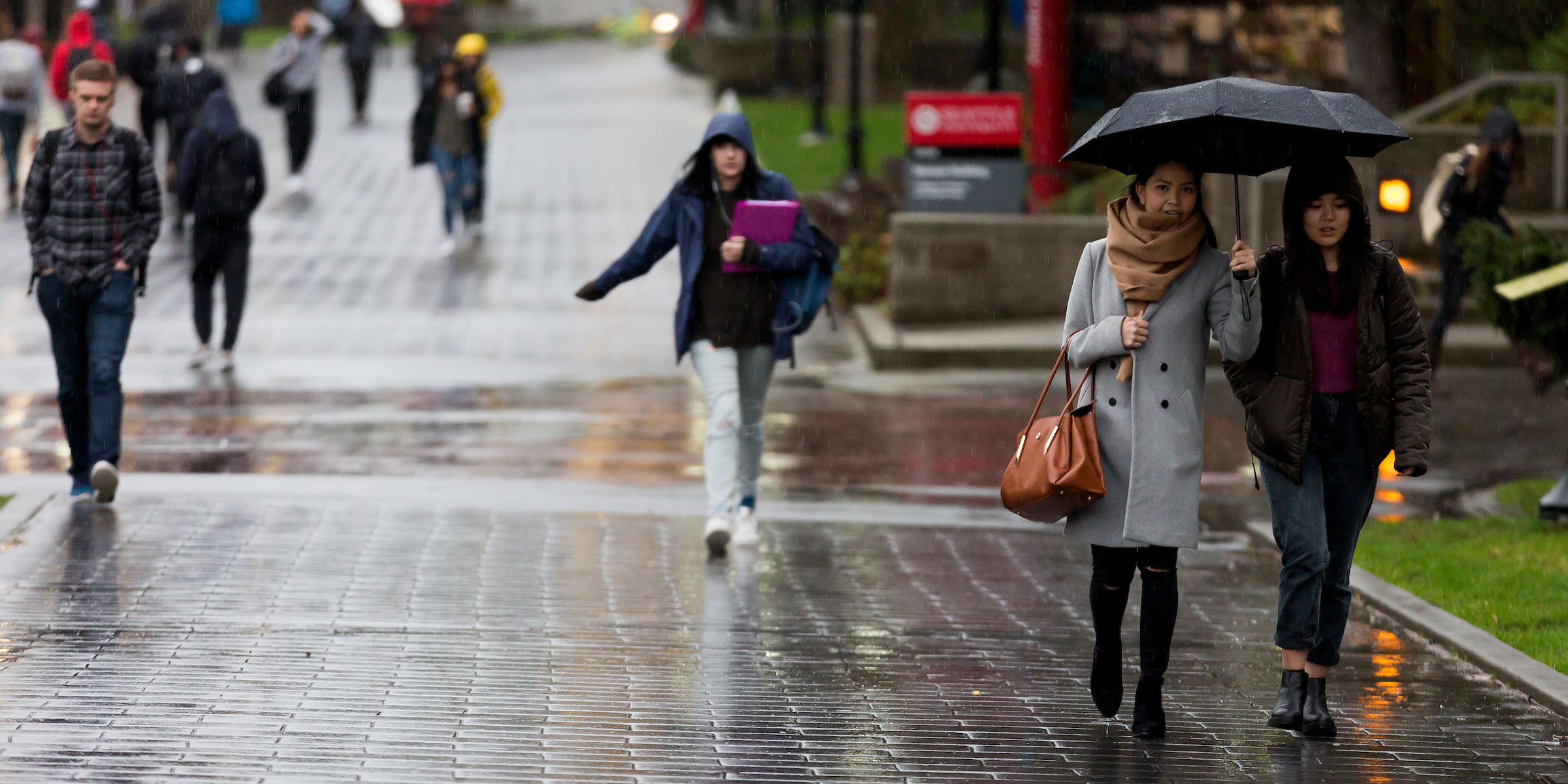 students walk through campus on a rainy day