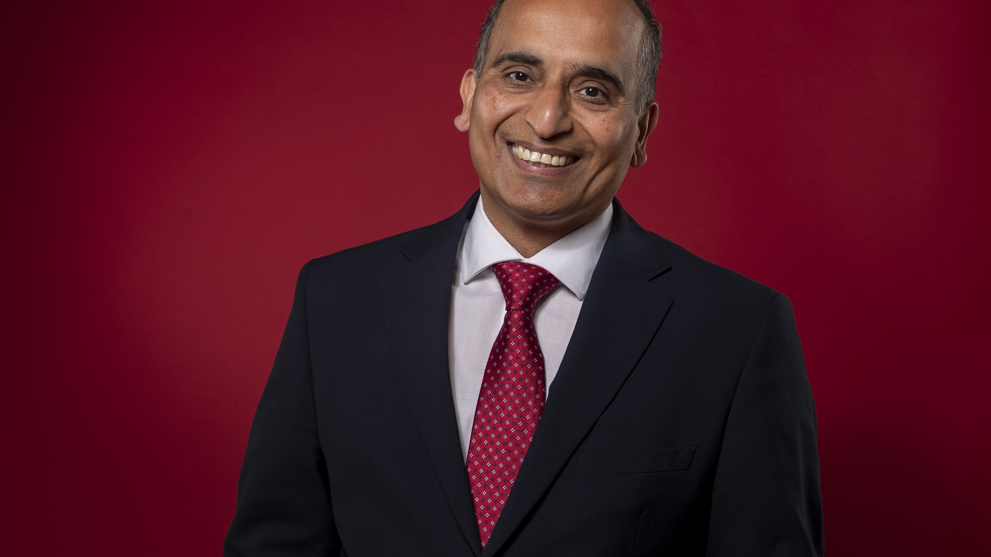 Amit in dark suit red tie