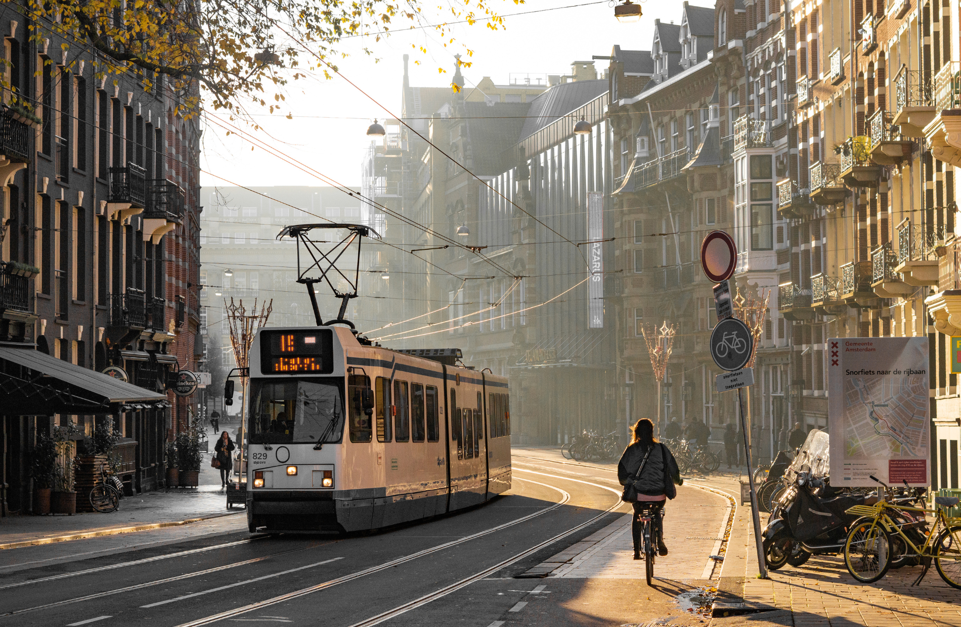 view of city street with a streetcar coming and bicyclist riding away