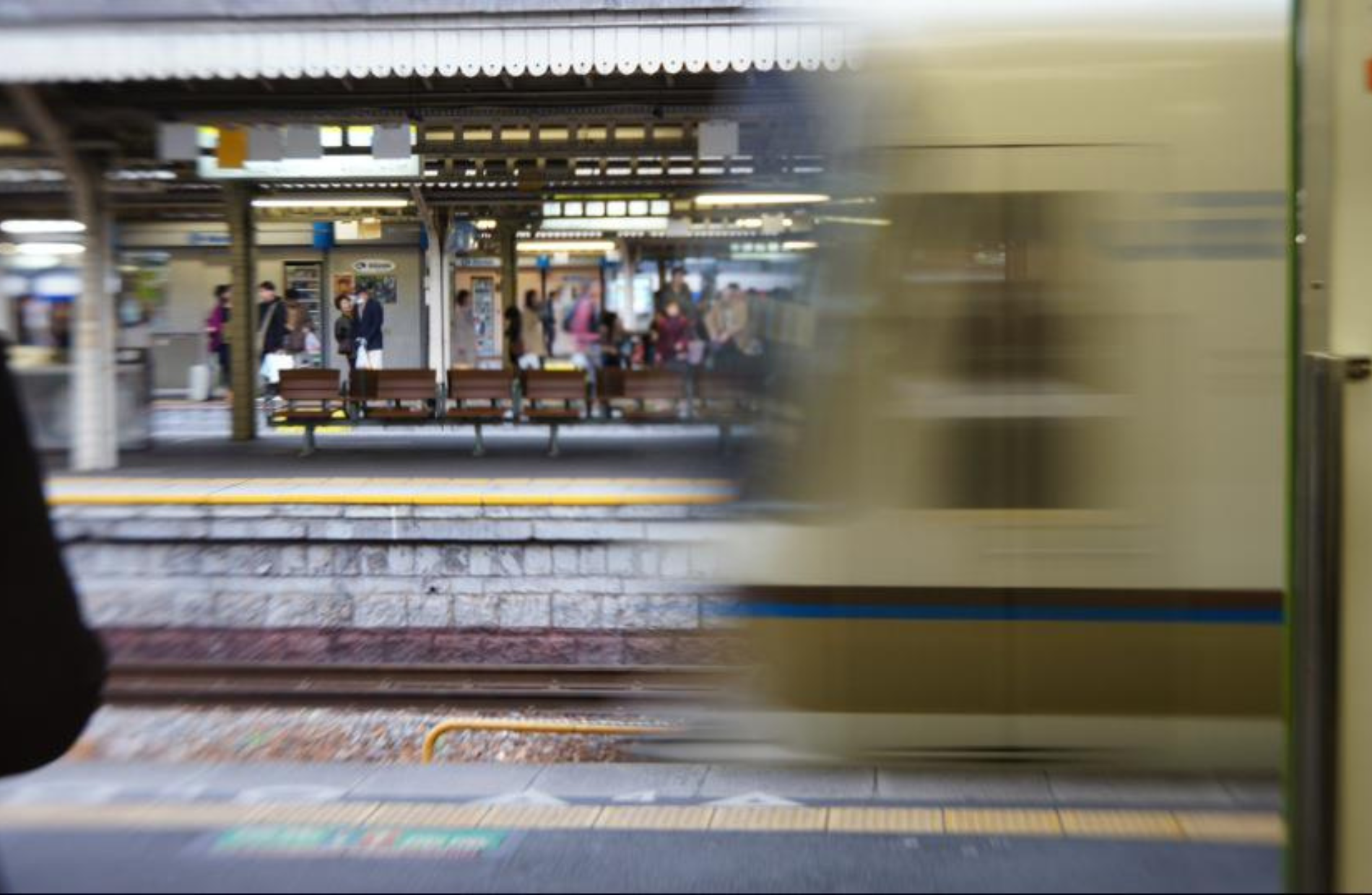 View of a station platform with a speeding train leaving the station