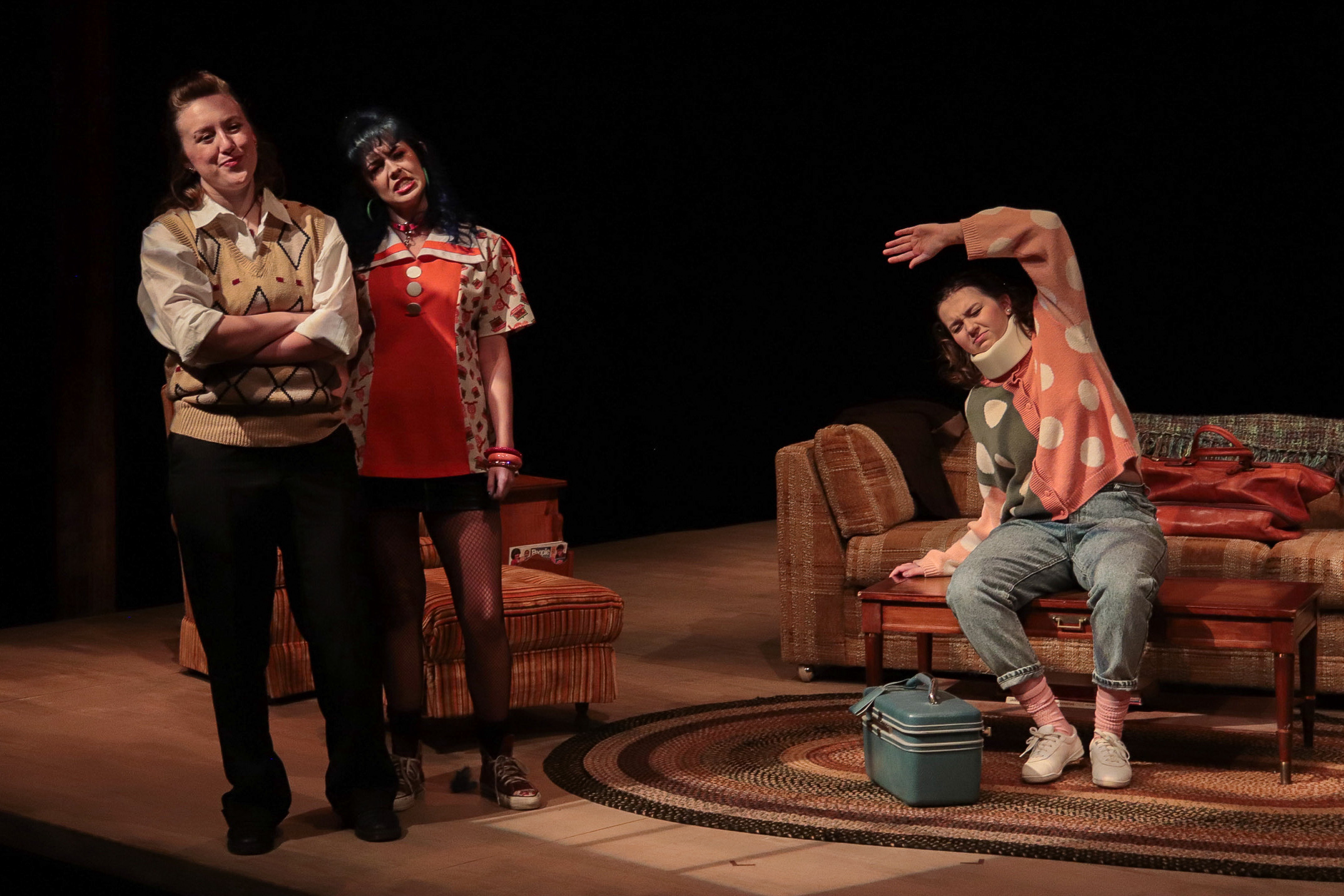 2 females staring in the distance and one sitting on a coffee table stretching, in-action shot
