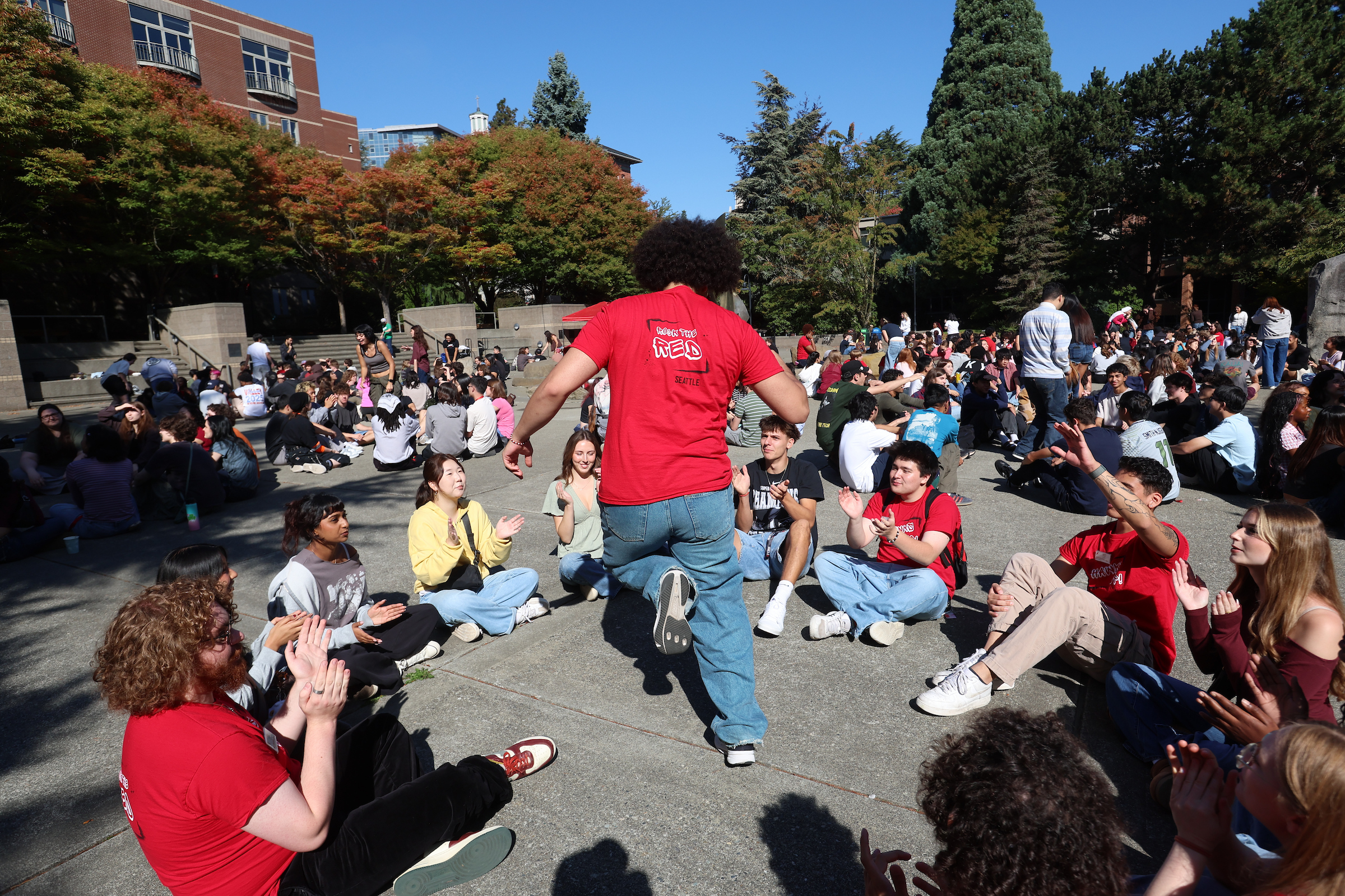 student dancing inside a circle of seated students in the quad