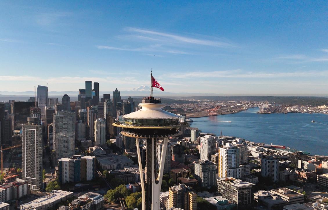 Phot of an flag with the SU interlock and the WCC (west coast confrence) logo. It is on top of the Space Needle.