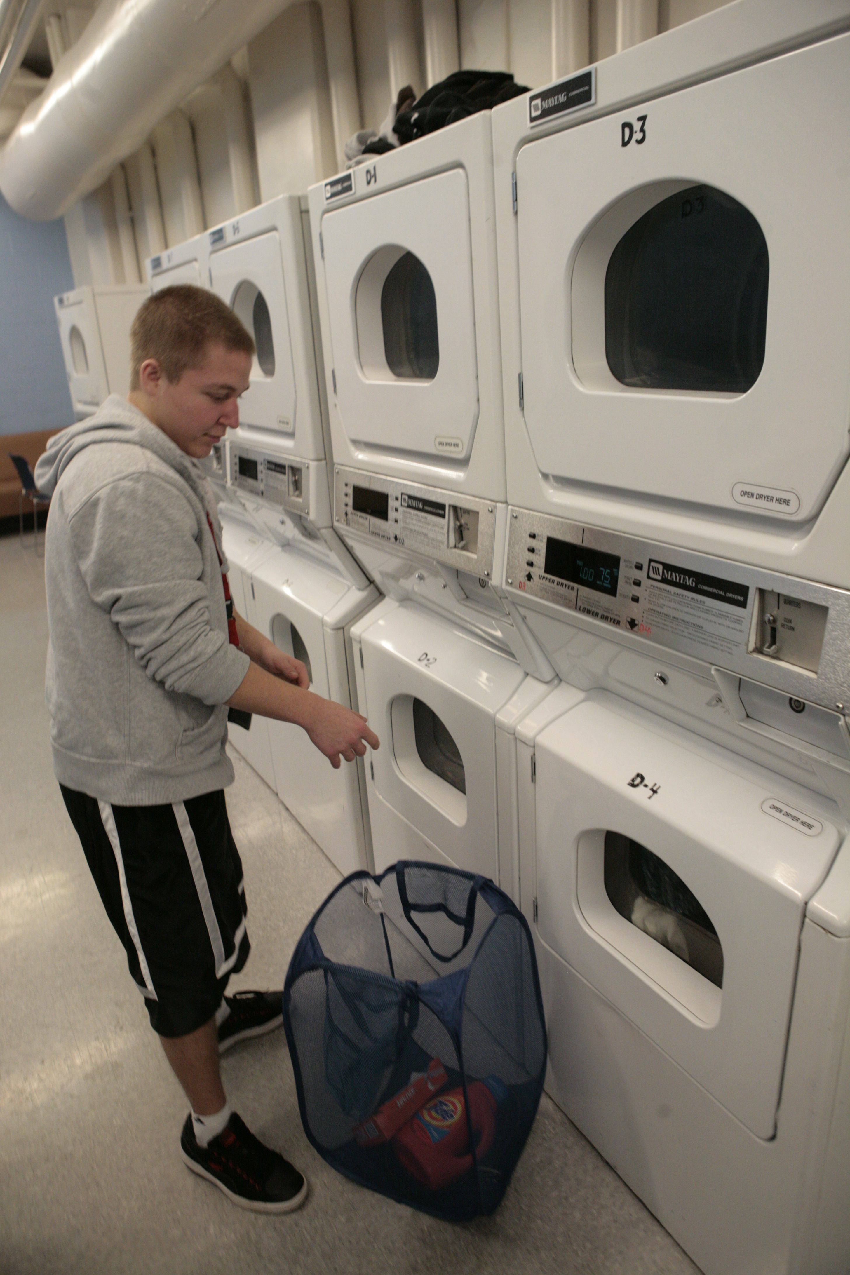 A student is putting laundry into a washing machine