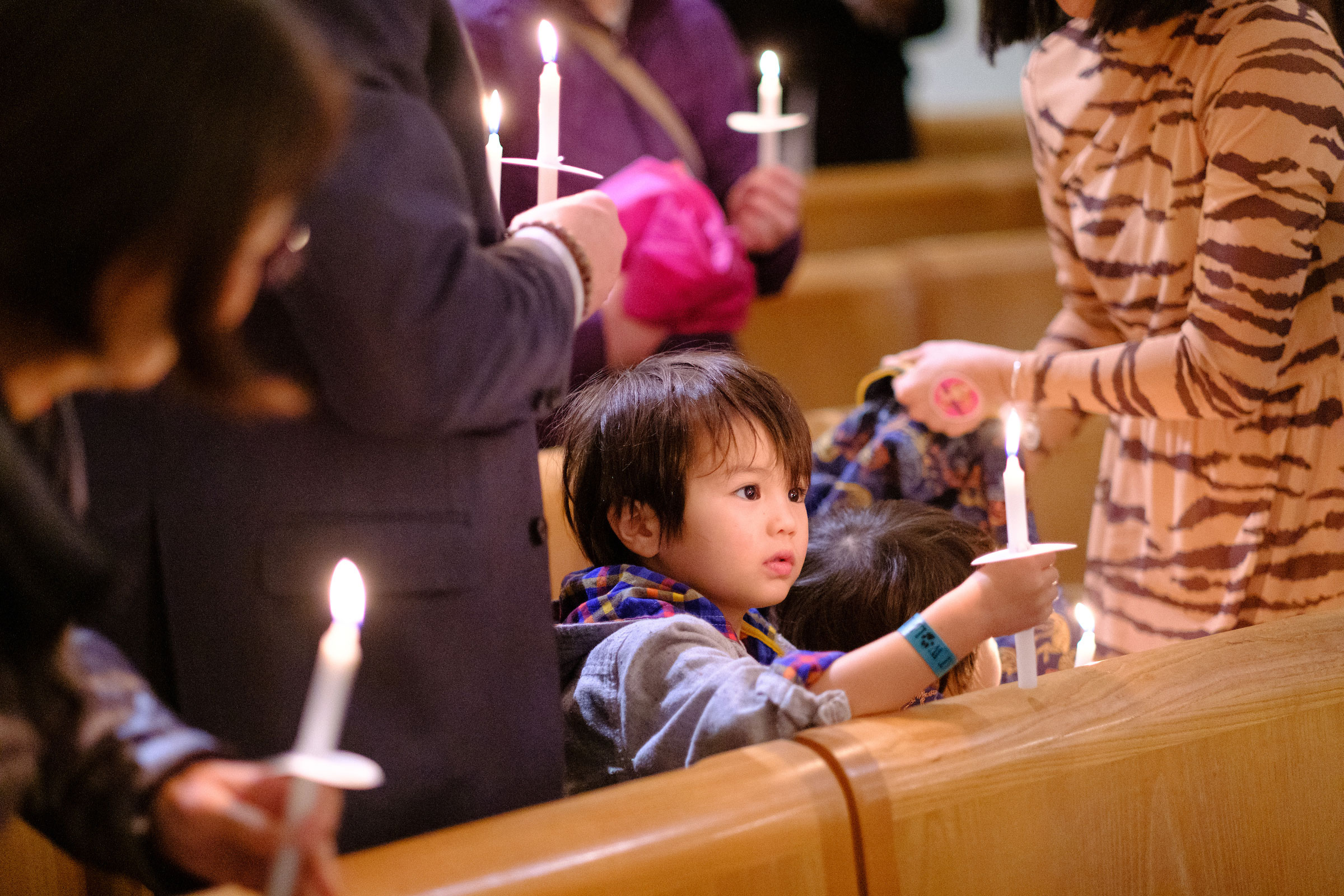 a young child holds a candle at the Advent Mass