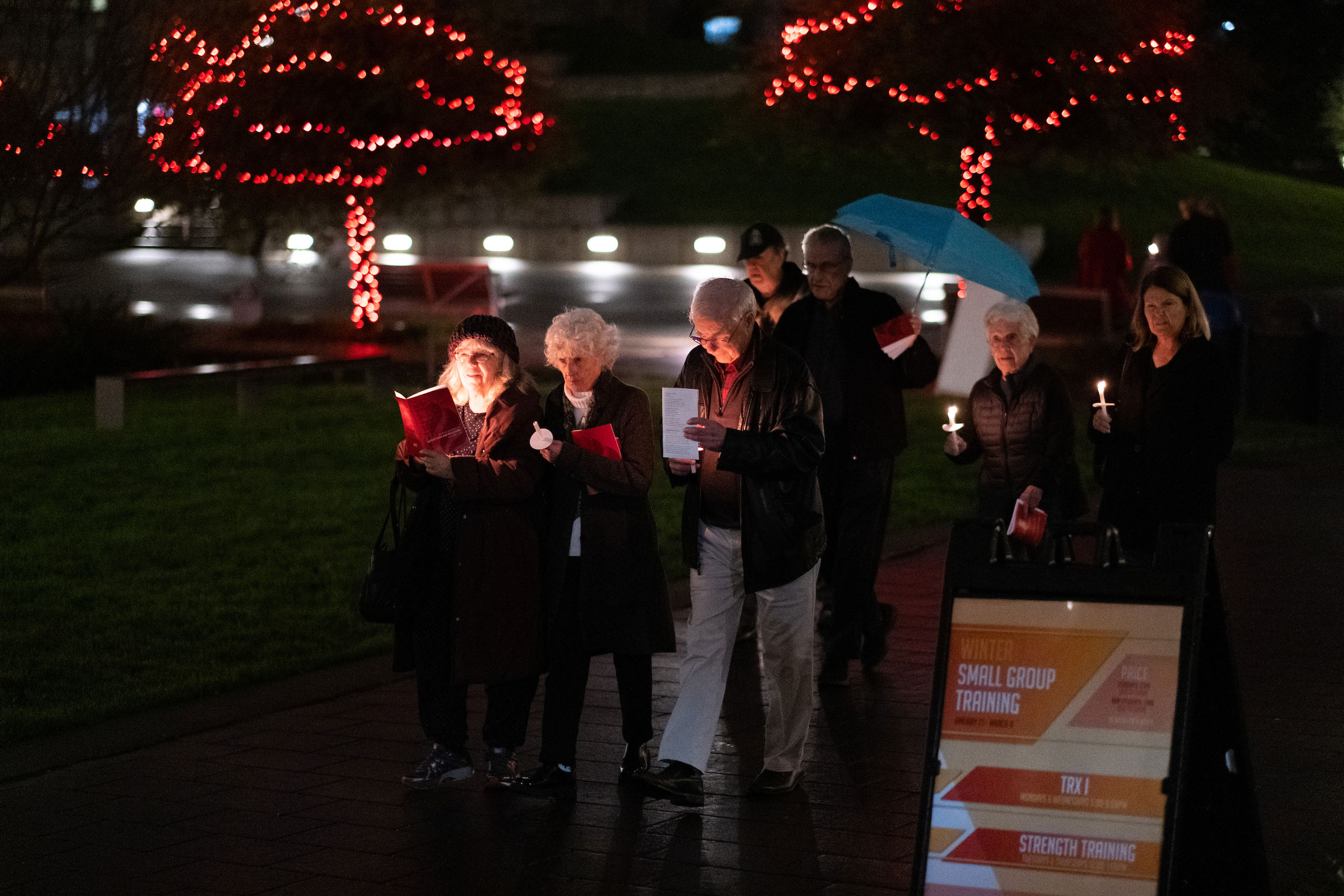 Advent Mass attendees walk with lit candles on campus