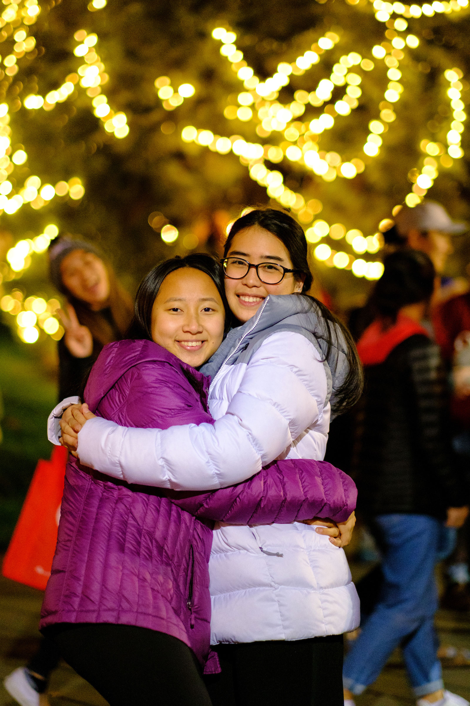 two students hugging in front of the campus Christmas Tree