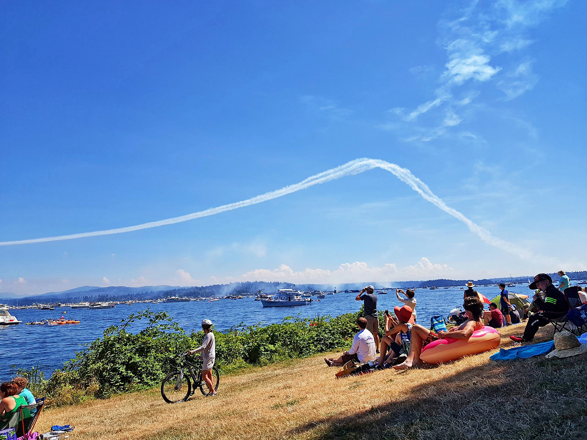 Seafair attendees at Lake Washington scan a blue sky filled with contrails for the Blue Angels